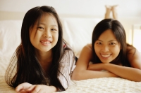 Mother and daughter lying on bed, looking at camera - Alex Microstock02