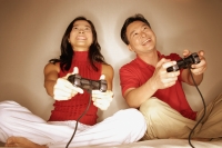 Man and woman playing with handheld video game, looking forward - Alex Microstock02