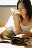Young woman lying on floor reading magazine. - Alex Microstock02