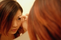 Woman looking at mirror, touching her eyebrows - Alex Microstock02