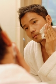 Young man applying shaving cream, looking in mirror - Alex Microstock02