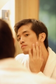 Young man touching his face, looking in mirror - Alex Microstock02