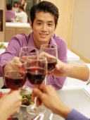 Friends toasting wine glasses across dinner table, over the shoulder view - Alex Microstock02