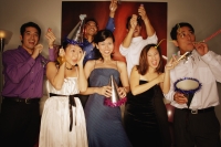 Group of friends having a party at home, playing with streamers and noisemakers - Alex Microstock02