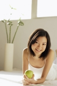 Young woman lying on front, holding green apple - Alex Microstock02