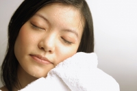Young woman wiping her face with towel, eyes closed - Alex Microstock02