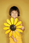 Young girl standing holding plastic sunflower. - Alex Microstock02