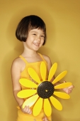 Young girl standing holding plastic sunflower, smiling - Alex Microstock02