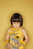 Young girl standing against yellow background, holding flowers - Alex Microstock02