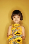 Young girl standing against yellow background, holding flowers, smiling - Alex Microstock02