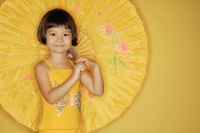 Young girl standing against yellow background, holding umbrella - Alex Microstock02