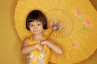 Young girl standing against yellow background, holding umbrella - Alex Microstock02