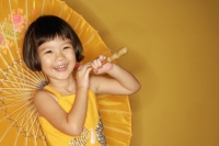 Young girl standing against yellow background, holding umbrella, laughing - Alex Microstock02