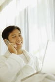 Young man wearing robe, using laptop and using mobile phone - Alex Microstock02