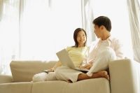 Young couple sitting on sofa, using laptop - Alex Microstock02
