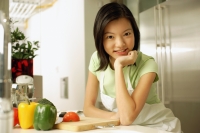 Young woman in kitchen, hand on chin, looking at camera - Alex Microstock02