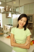 Young woman leaning on kitchen counter, arms crossed, looking at camera - Alex Microstock02