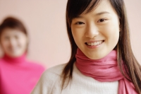 Young woman with scarf smiling, another woman in background - Alex Microstock02