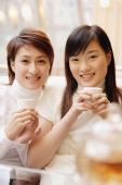 Young women holding teacups, looking at camera - Alex Microstock02