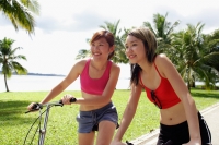 Two women on bicycles, side by side, looking forward - Alex Microstock02