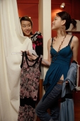Two women trying on clothes at shop, one behind curtain - Alex Microstock02