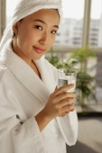  Young woman in robe holding glass of water, looking at camera - Alex Microstock02