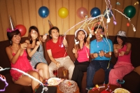 Young adults celebrating with crackers, party hats and balloons - Alex Microstock02