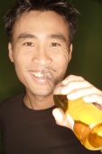  Young man holding beer bottle to his lips, looking at camera - Alex Microstock02