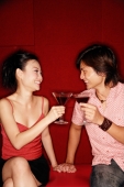 Couple sitting side by side, toasting with drinks - Alex Microstock02