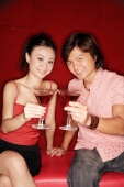 Couple sitting side by side, holding drinks, looking at camera - Alex Microstock02