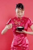 Woman in Cheongsam, holding bowl of rice and chopsticks, looking down - Alex Microstock02