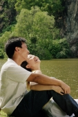 Couple sitting by lake, laughing - Alex Microstock02