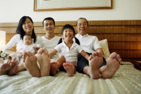 Three generation family on bed, looking at camera, low angle view - Jade Lee