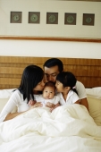 Father, mother and daughter kissing baby daughter - Jade Lee