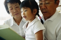 Grandparents with granddaughter, reading a book - Jade Lee