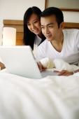 Couple in bedroom looking at laptop - Jade Lee