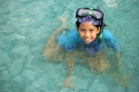 Young girl in swimming pool with goggles, looking up at camera - Jade Lee