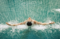Man in swimming pool, water cascading over him - Alex Microstock02
