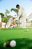 Senior couple playing golf, woman with golf club, man crouching down - Alex Microstock02