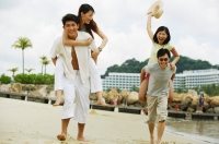 Couples on beach, men carrying women on their backs - Jade Lee