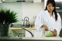 Woman in kitchen, cutting cucumber - Jade Lee