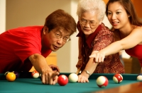 Father and daughter teaching grandmother to play pool - Jade Lee