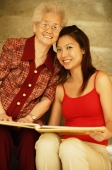 Grandmother with granddaughter, holding picture album - Jade Lee