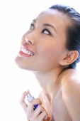 Woman applying perfume, looking up, smiling - Alex Microstock02