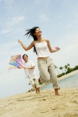 Couple flying kite along beach, woman running in front of man - Alex Microstock02