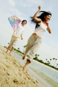Couple flying kite along beach, woman running in front of man - Alex Microstock02