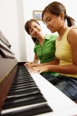 Mother and daughter sitting side by side in front of piano, mother with hand on daughter's shoulder - Alex Microstock02