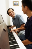 Father and son sitting at piano, looking at each other - Alex Microstock02