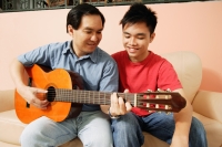 Father and son side by side, father holding guitar - Alex Microstock02