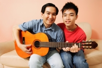 Father and son side by side, holding guitar, looking at camera - Alex Microstock02
